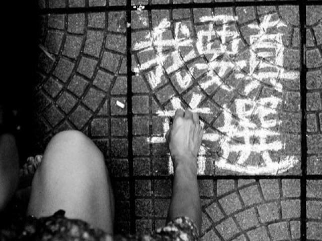 person writing chinese characters on ground
